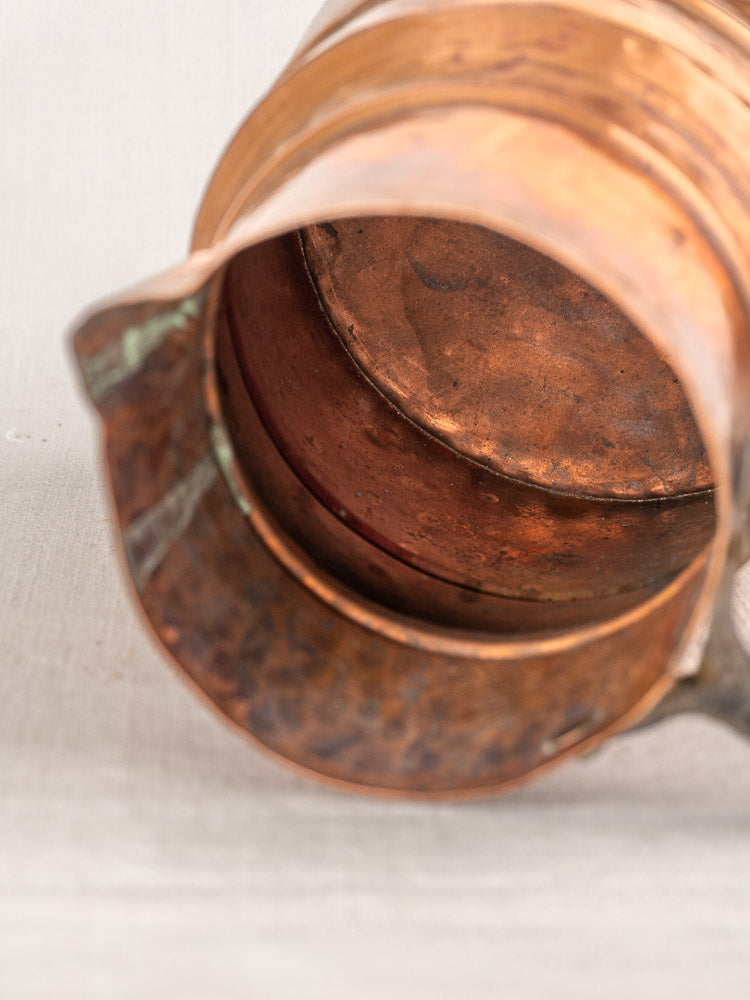 Antique French copper measure jug, 19th century, hand-hammered with iron handle, shown on its side against a light background.