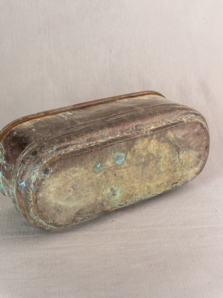 Antique French copper jardinière with verdigris patina and rounded base displayed on neutral fabric.