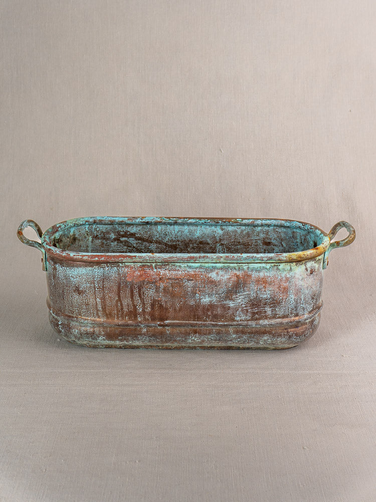 Antique French copper poissonnière jardinière with two handles and verdigris patina on a neutral background.