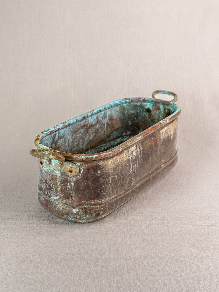 Antique French copper poissonnière jardinière with verdigris patina, two handles, rectangular shape; beige background.
