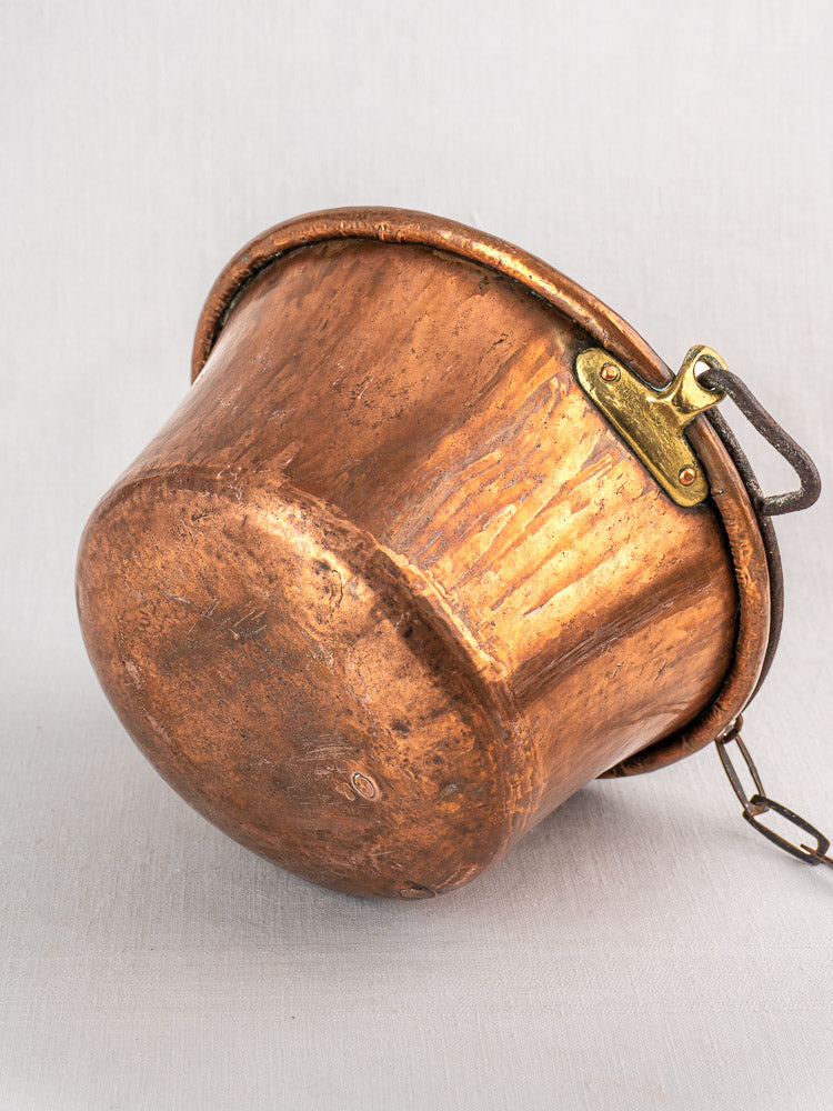 Antique French copper hearth pot with iron bail handle and chain, notable age and patina.
