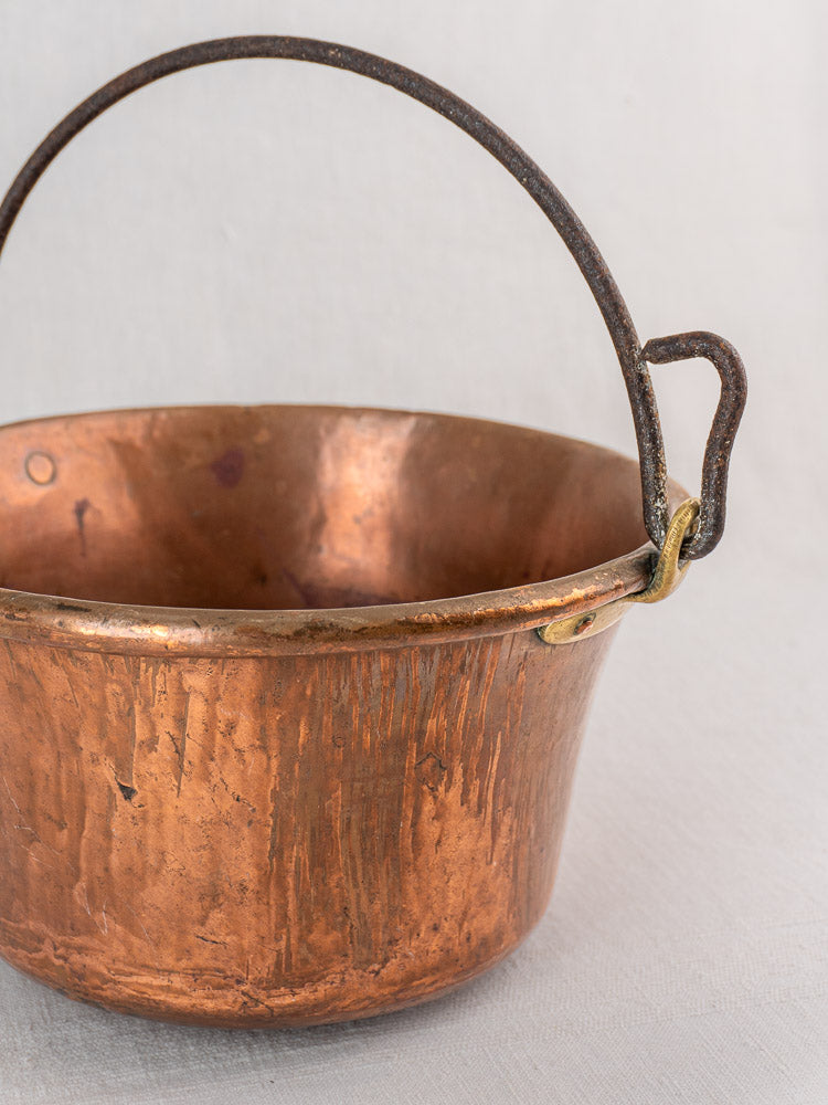 Antique French copper hearth pot with iron bail handle and chain, showing patina and scratches.