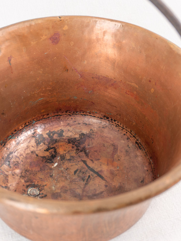 Antique French copper hearth pot with worn, stained interior and iron bail handle with chain.