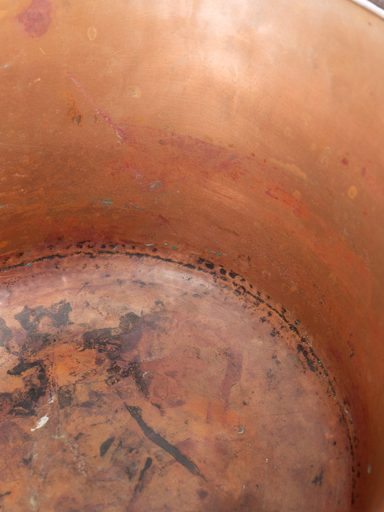 Interior of antique French copper hearth pot with tarnish, discoloration, dark spots, and scratches.