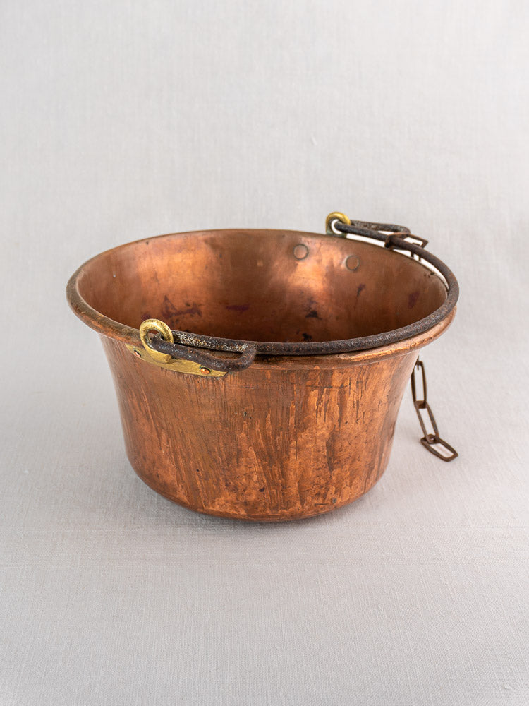 Antique French copper hearth pot with iron bail handle and chain on a plain background.