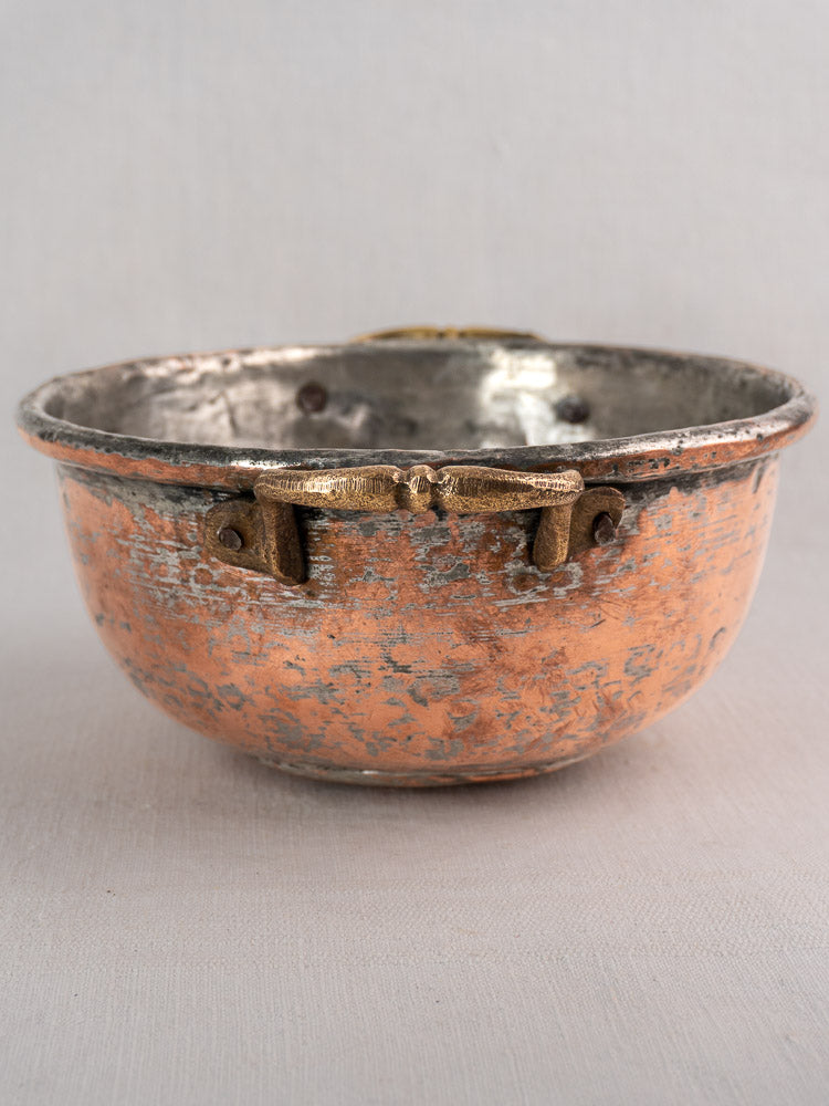 Antique French copper bowl with brass handles, early 19th century, shown on a neutral surface and plain background.