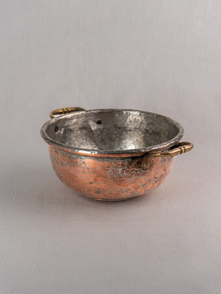 Antique French copper bowl with brass handles and silver-toned interior on a neutral surface, light gray background.