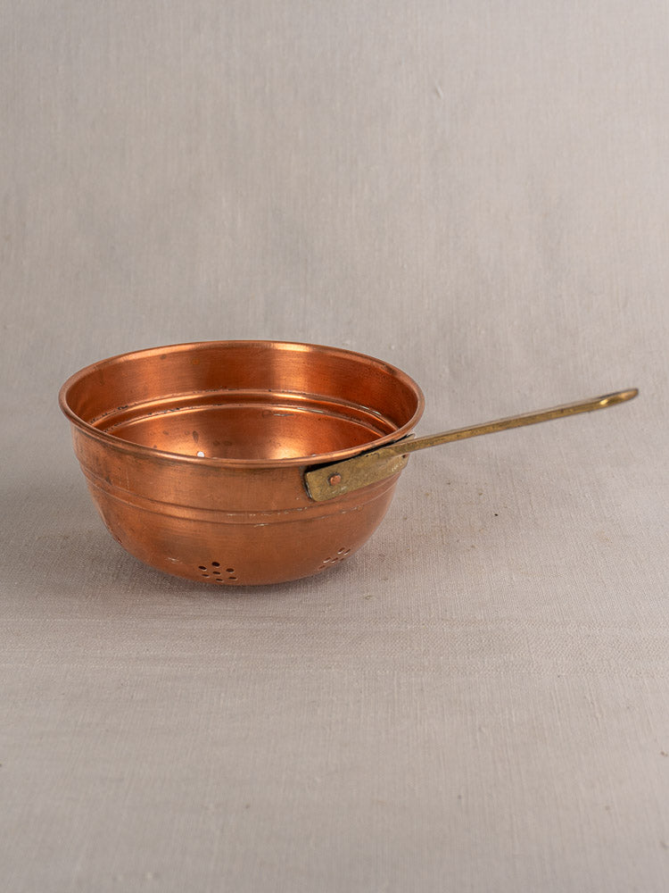 Antique French copper strainer set with brass handles, three colanders shown on a neutral fabric backdrop.