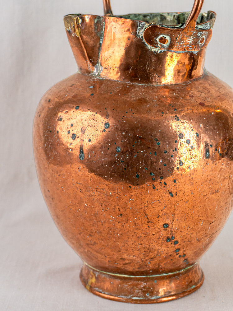 Antique French hand-raised copper double-spout water jug with bent rim and green patina.