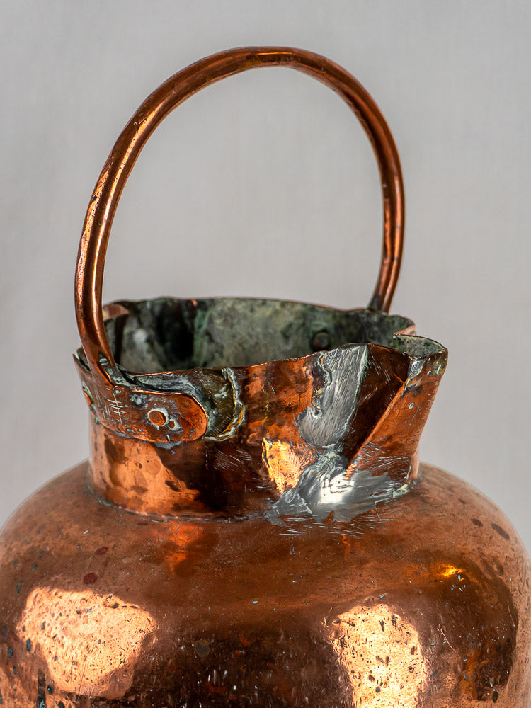 French antique hand-raised copper water jug with double spout, curved handle, and uneven rim.
