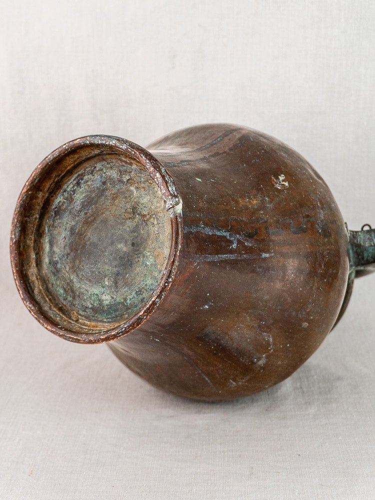 Antique French copper water jug with rounded base, hand-worked 19th-century pichet on light background.