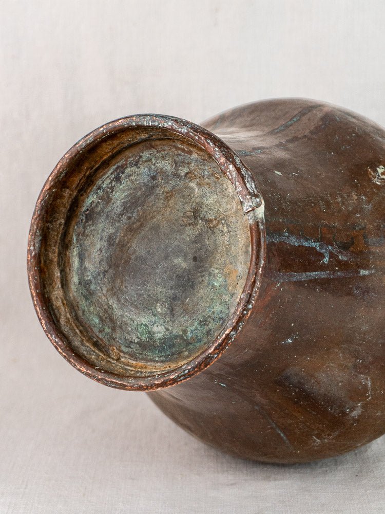 Close-up of a weathered brown ceramic pot base with visible chipping and discoloration on fabric backdrop.