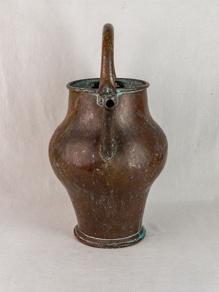 Antique French copper water jug with rounded body, narrow neck, curved handle, and spout on plain background.