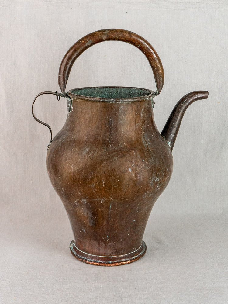 Antique French copper water jug with wide body, curved handle, and slender spout on fabric.