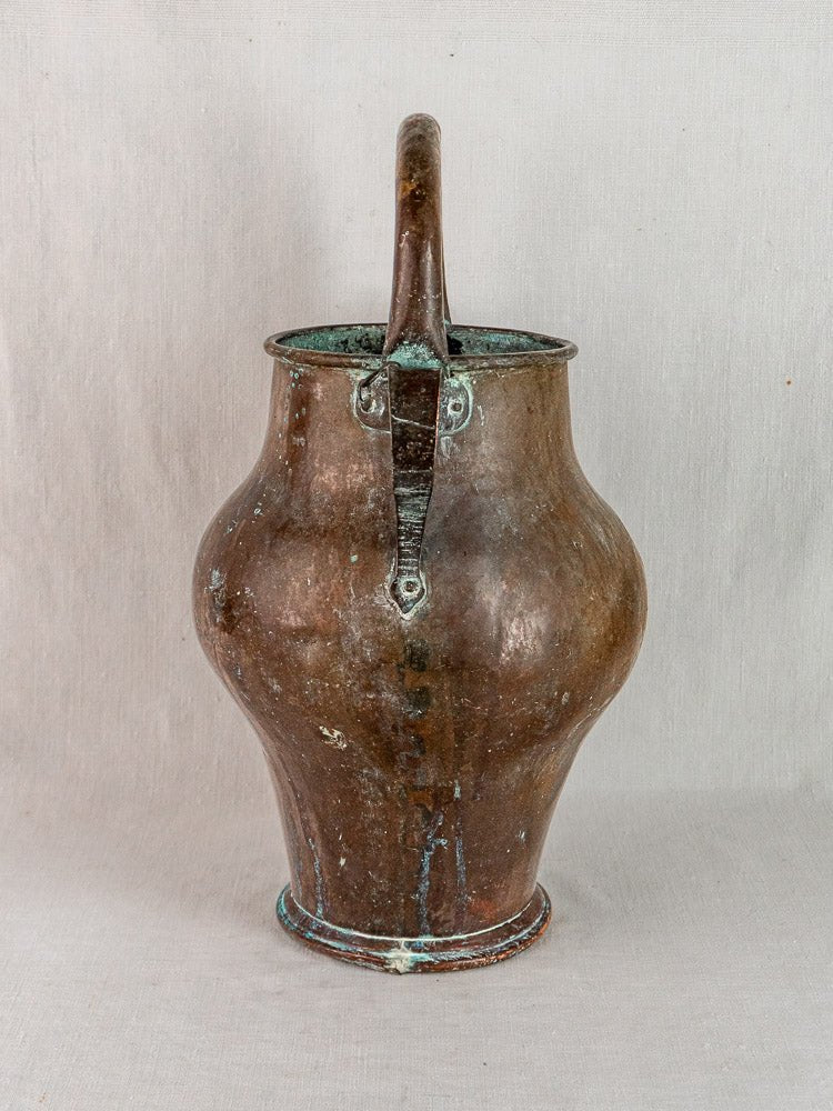 Antique 19th-century French copper water jug with rounded body, narrow neck, arched handle, on light gray background.