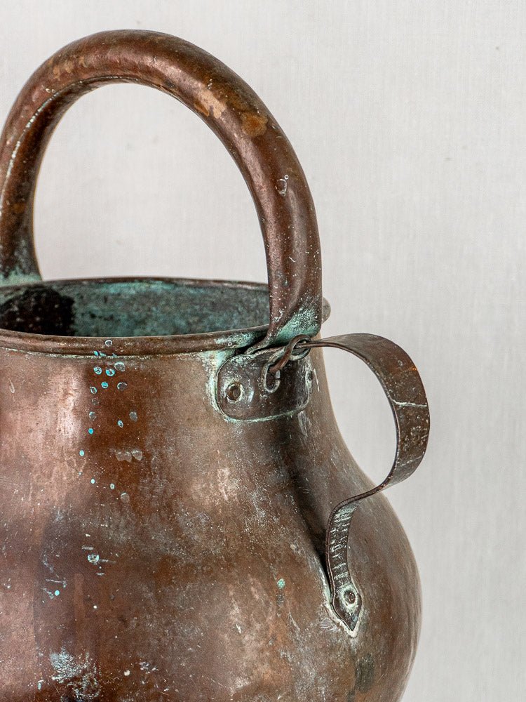 Antique French copper water jug with curved handle, side latch, and visible greenish patina.