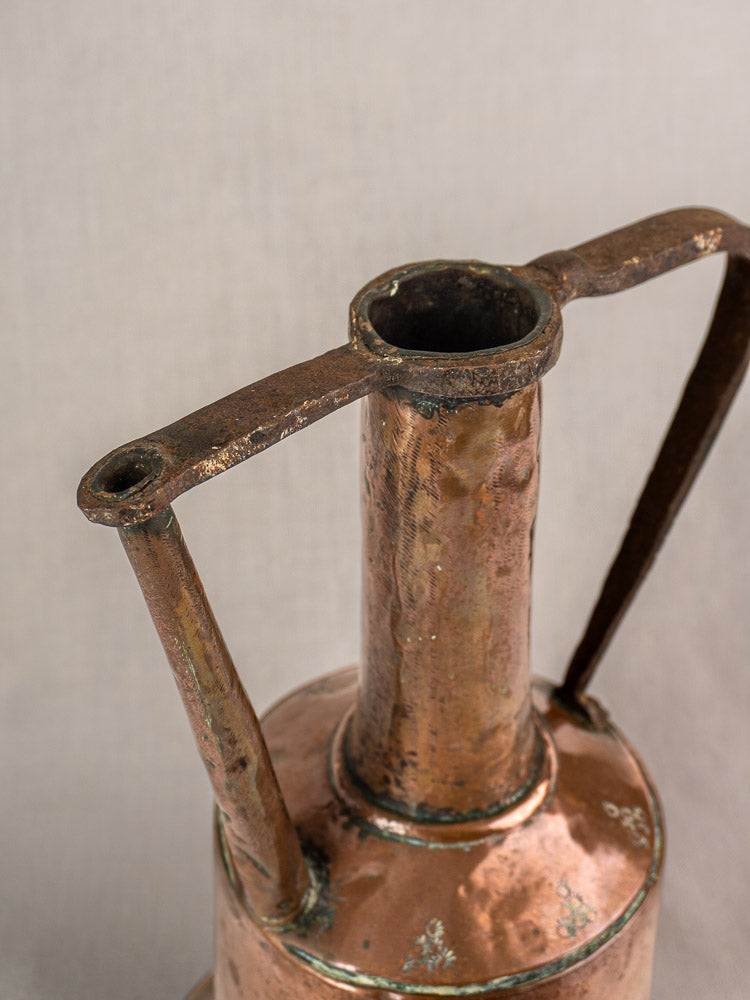 Antique French hand-hammered copper water jug with tall neck and iron handles, rich patina, neutral background.