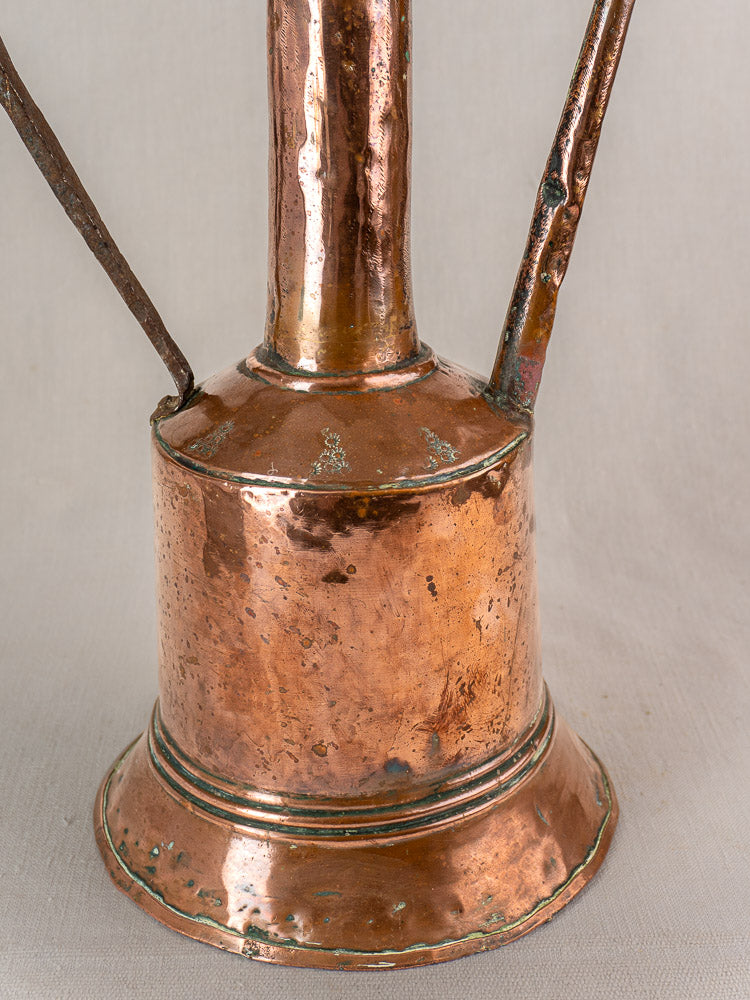 Antique French copper water jug with iron handles, hand-hammered surface, cylindrical body, and flared base.