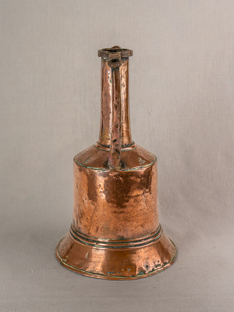 Antique French copper water jug with iron handles and hand-hammered finish on neutral fabric background.