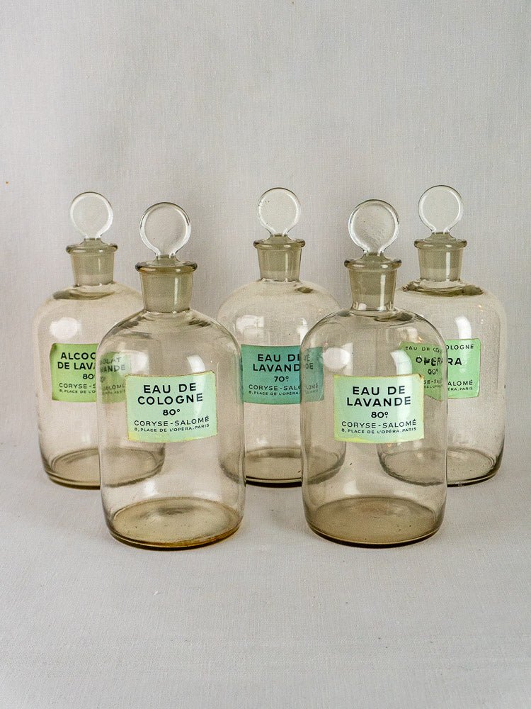 Set of 5 Coryse-Salomé French glass perfume bottles with round stoppers and green labels, white background.