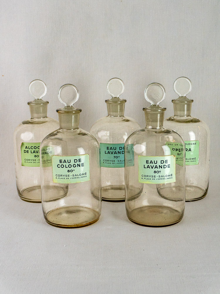 Set of 5 Coryse-Salomé French glass perfume bottles with round stoppers and green labels, white background.