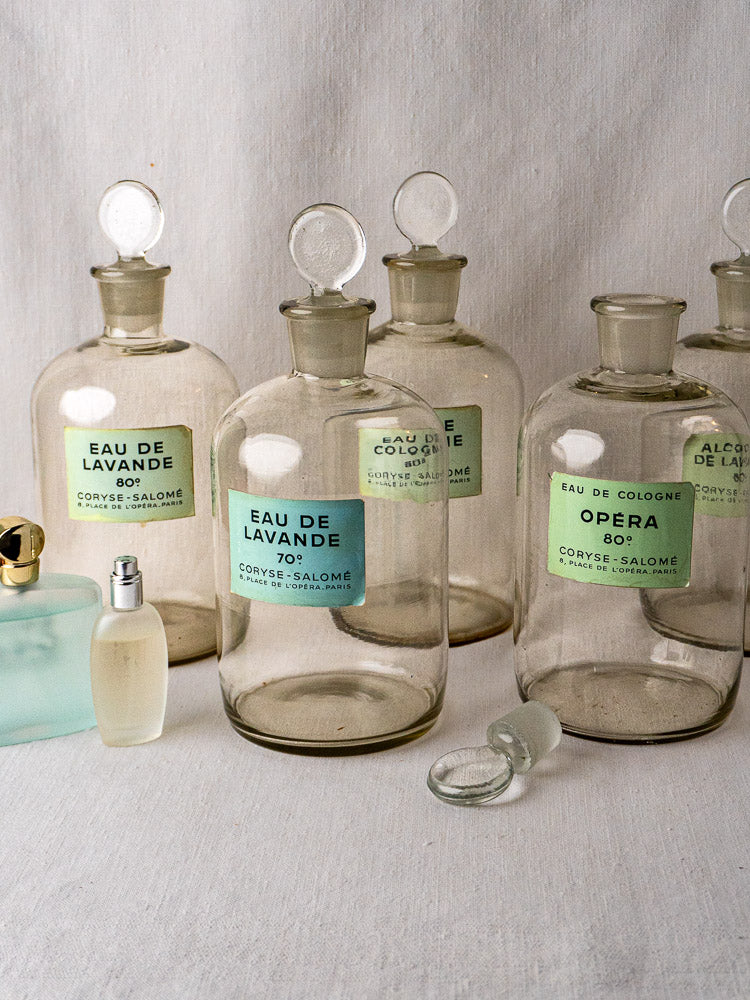 Set of five French Coryse-Salomé perfume bottles with pastel labels and glass stoppers on fabric.