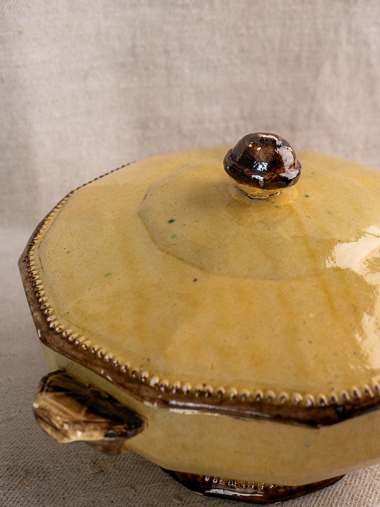 Antique French Vallauris Beretta et Cie mustard glaze pottery pot with brown accents on textured beige fabric.