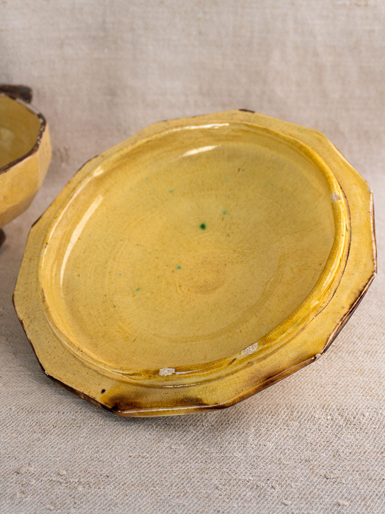 Vintage Vallauris Beretta et Cie round ceramic plate with scalloped edge and mustard glaze on beige fabric.