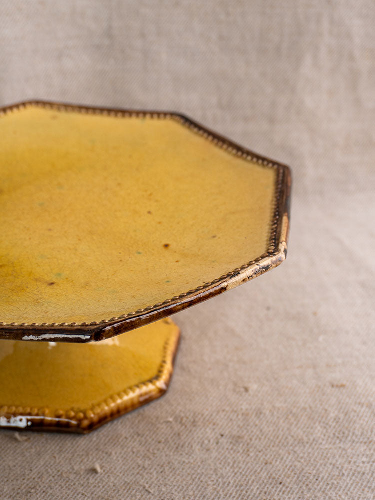 Antique French Vallauris Beretta et Cie ceramic table service, mustard glaze, octagonal, rustic finish on textured beige fabric.