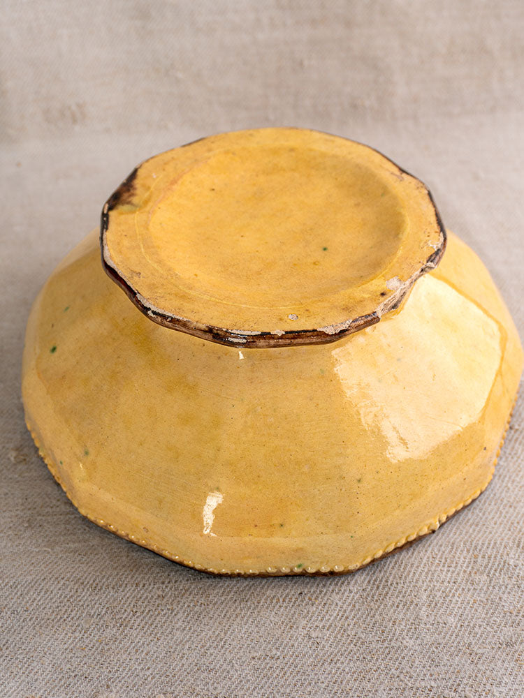 Upside-down yellow-glazed ceramic bowl with rough rim on beige fabric, from Vallauris Beretta et Cie table service set.
