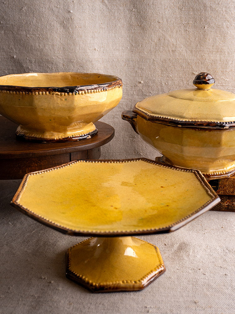 Vallauris Beretta et Cie mustard-glazed three-piece pottery set with bowl, lidded tureen, and cake stand on beige cloth.