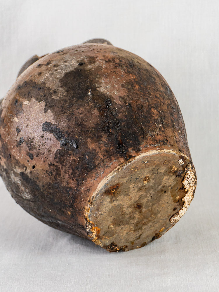 Bottom of 18th-century French Orjol terracotta jar with aged base, stains, and wear on light surface.