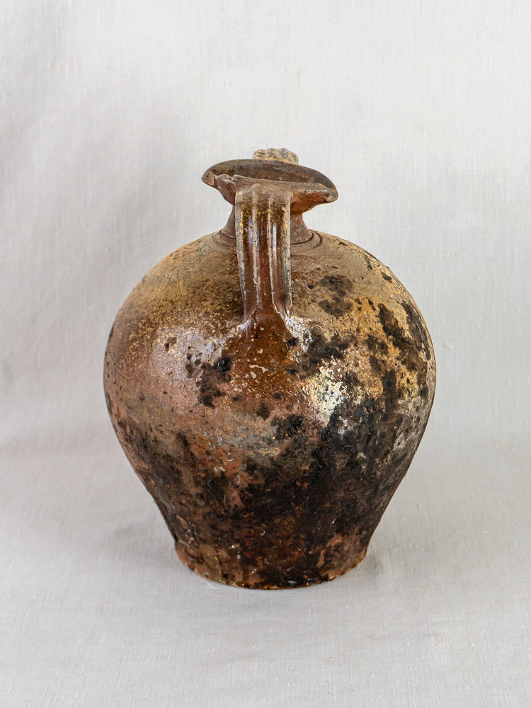 Antique French Orjol terracotta pouring jar with two handles, narrow neck, and textured surface.