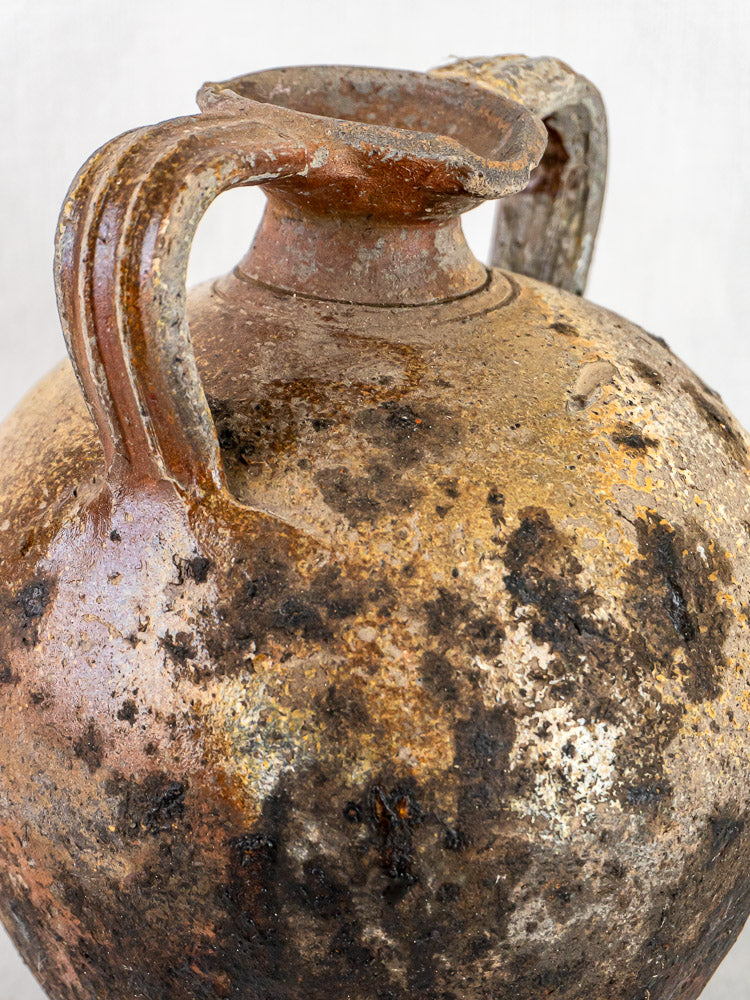 Antique French Orjol terracotta pouring jar with dual handles, weathered surface, and dark discoloration.