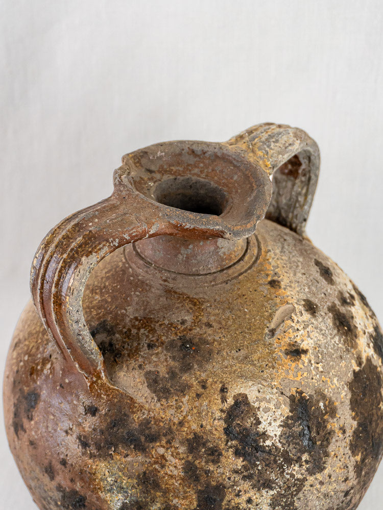 Antique French Orjol, 18th-century terracotta pouring jar with age-worn, mottled surface on plain background.