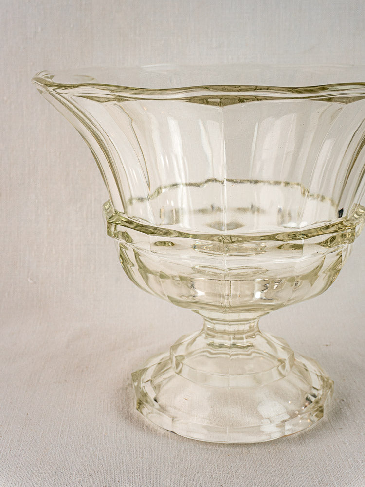 Antique French glass Coupe Médicis compotier with flared rim and faceted base on textured surface.