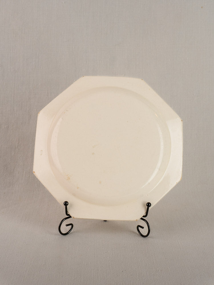 Antique French creamware plate with octagonal beaded rim, 19th century, on black stand, neutral gray background.