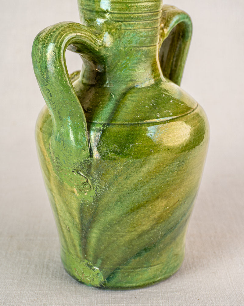 Antique French green glazed earthenware cruche with two curved handles, devotional medallion, and textured swirling patterns.