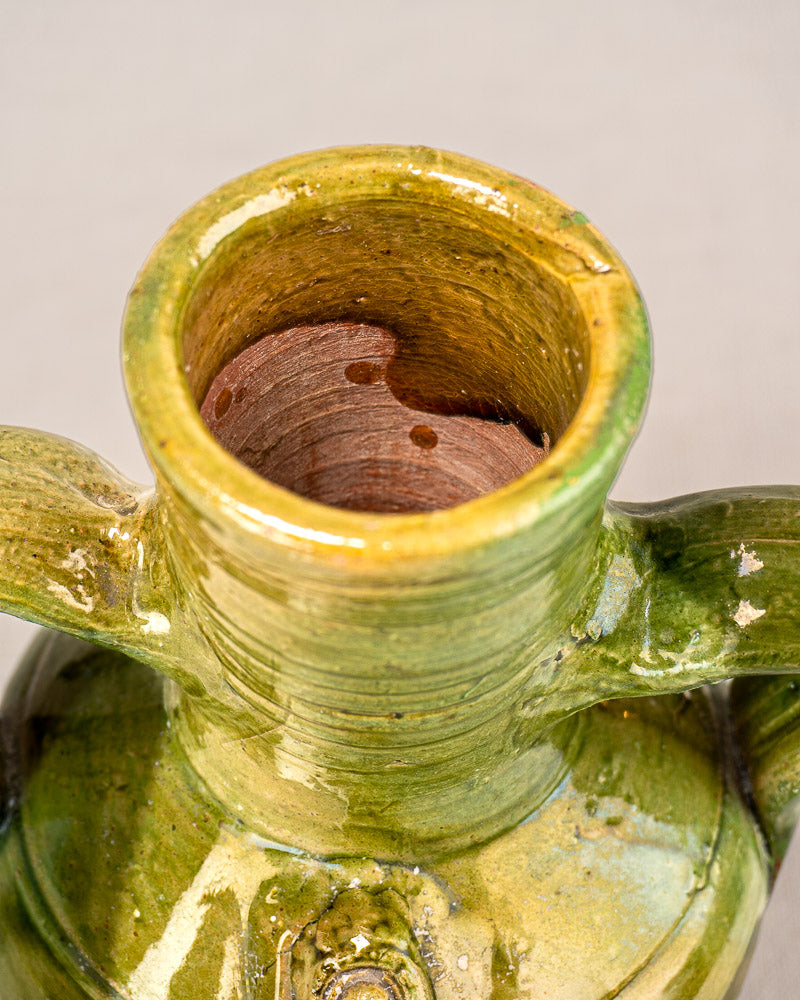 Antique French green-glazed earthenware cruche with two handles, reddish-brown interior, Pyrenean style, and devotional medallion.