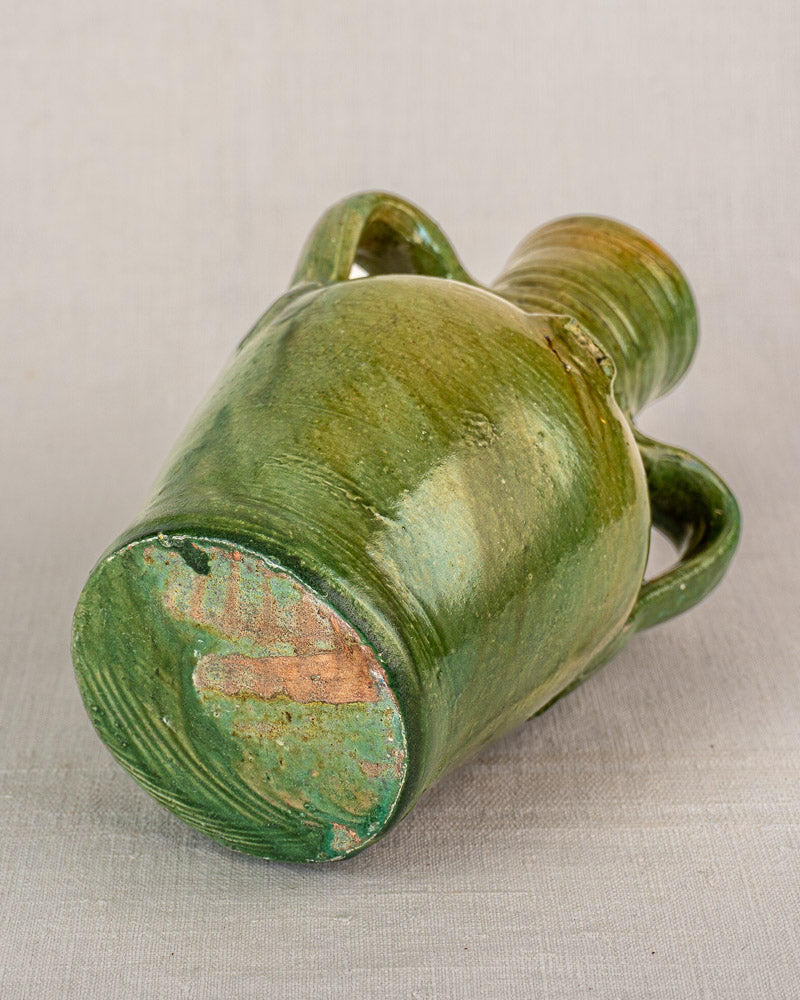 Antique French green glazed earthenware cruche with two handles, devotional medallion, and textured reddish clay base.
