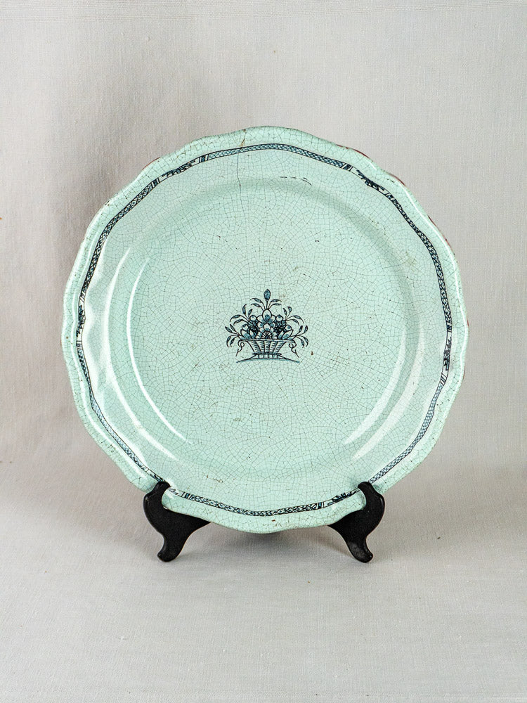 Antique celadon French faience charger with scalloped rim, black floral motif, and crackled glaze.