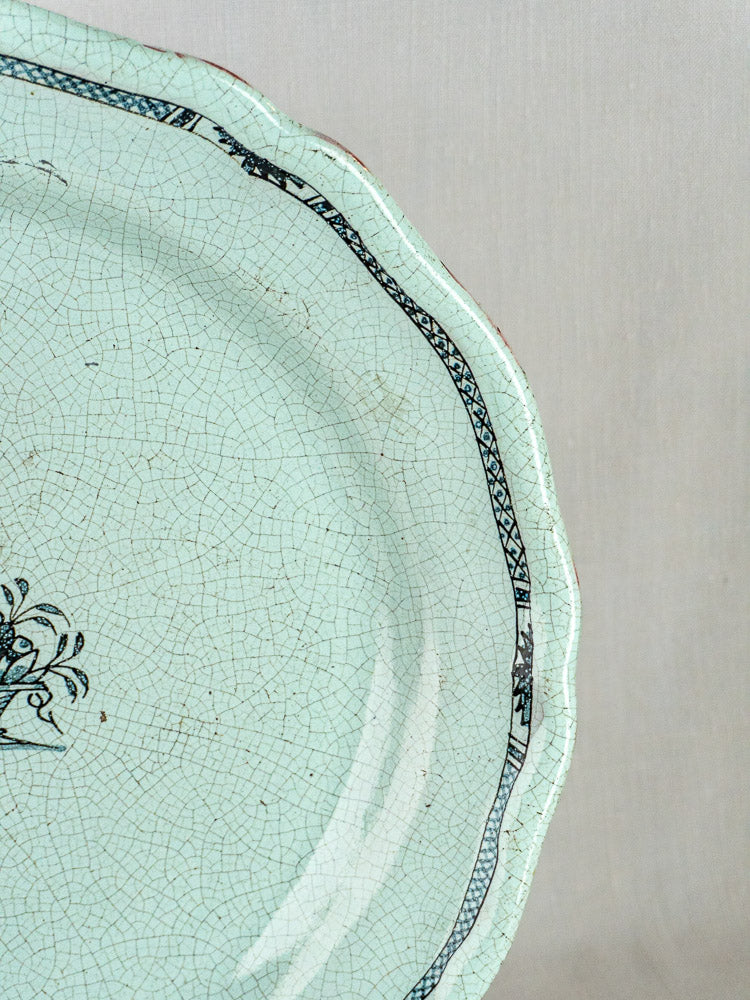 Antique French faience celadon charger with crackle glaze, scalloped rim, and black border detailing.