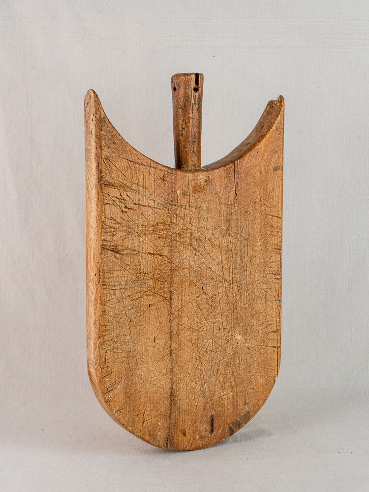 Antique French hand-carved wood cutting board with winged shoulders, rounded base, and knife marks.