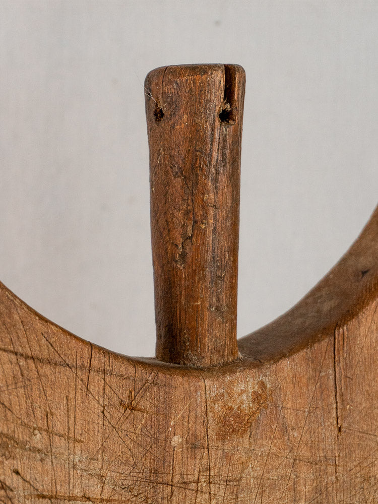 Antique French hand-carved wing-shouldered wooden cutting board with vertical handle, set on a light background.