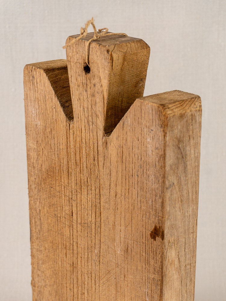 Antique French hand-carved oak cutting board, late 19th century, notched top, twine-threaded hole, on neutral background.