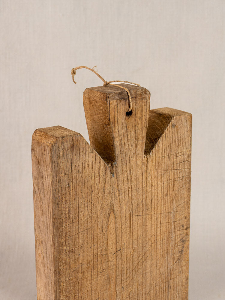 Antique French oak cutting board, late 19th century, with V-notch and string loop; weathered wood against neutral background.