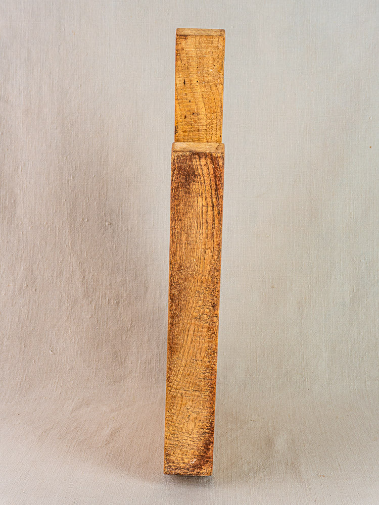 Antique French hand-carved wood cutting board with thick profile and visible grain, upright on a neutral background.