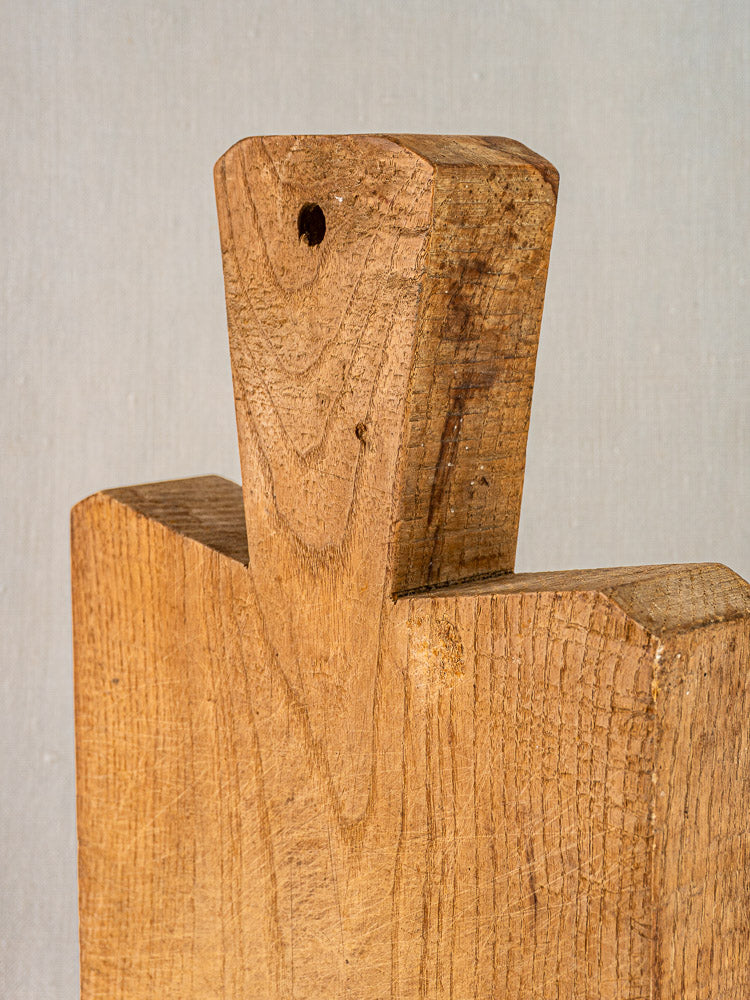 Antique French cutting board with hand-carved dovetail joint, interlocking unfinished wood, grain patterns, and drilled hanging hole.