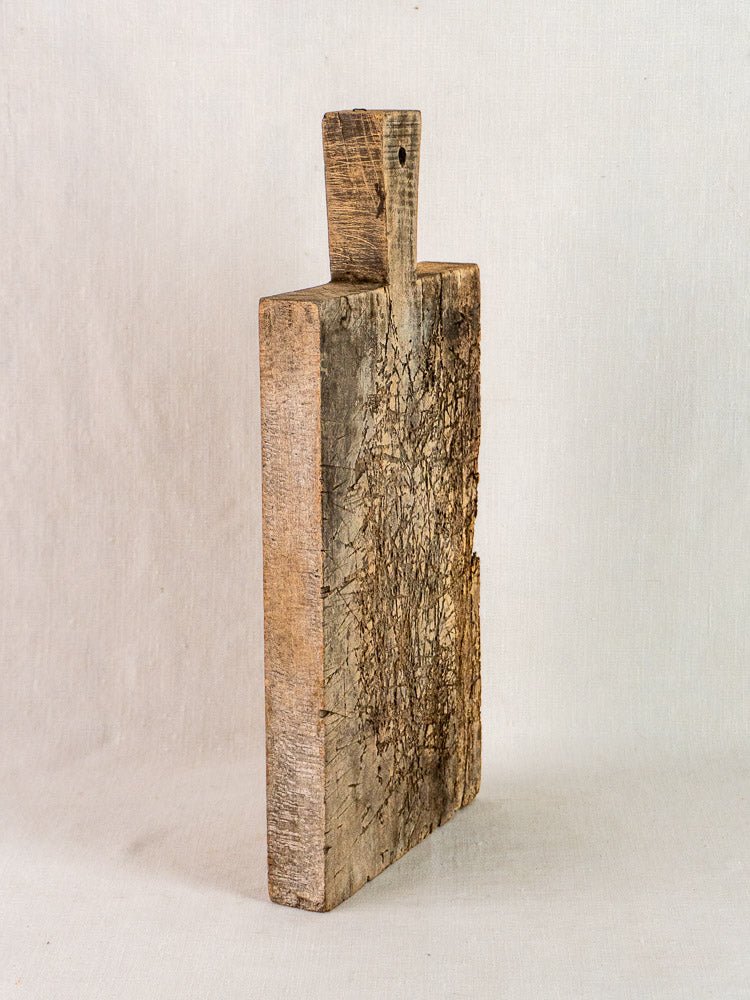 Antique French wooden cutting board with handle, richly patinated and worn, late 19th century.
