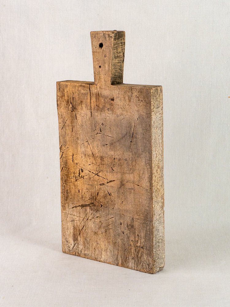 Late 19th-century French antique solid wood cutting board with rectangular shape and short handle, aged patina.